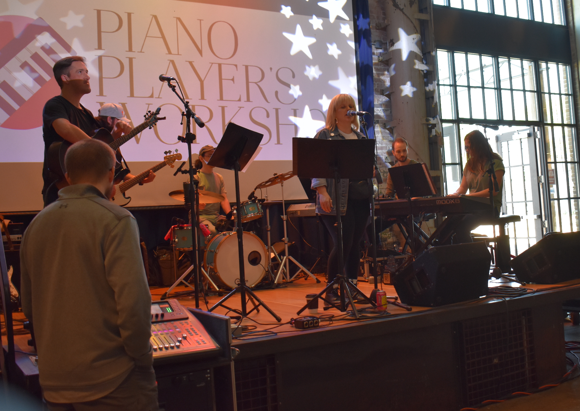 Full student band on stage under Piano Player's Workshop banner