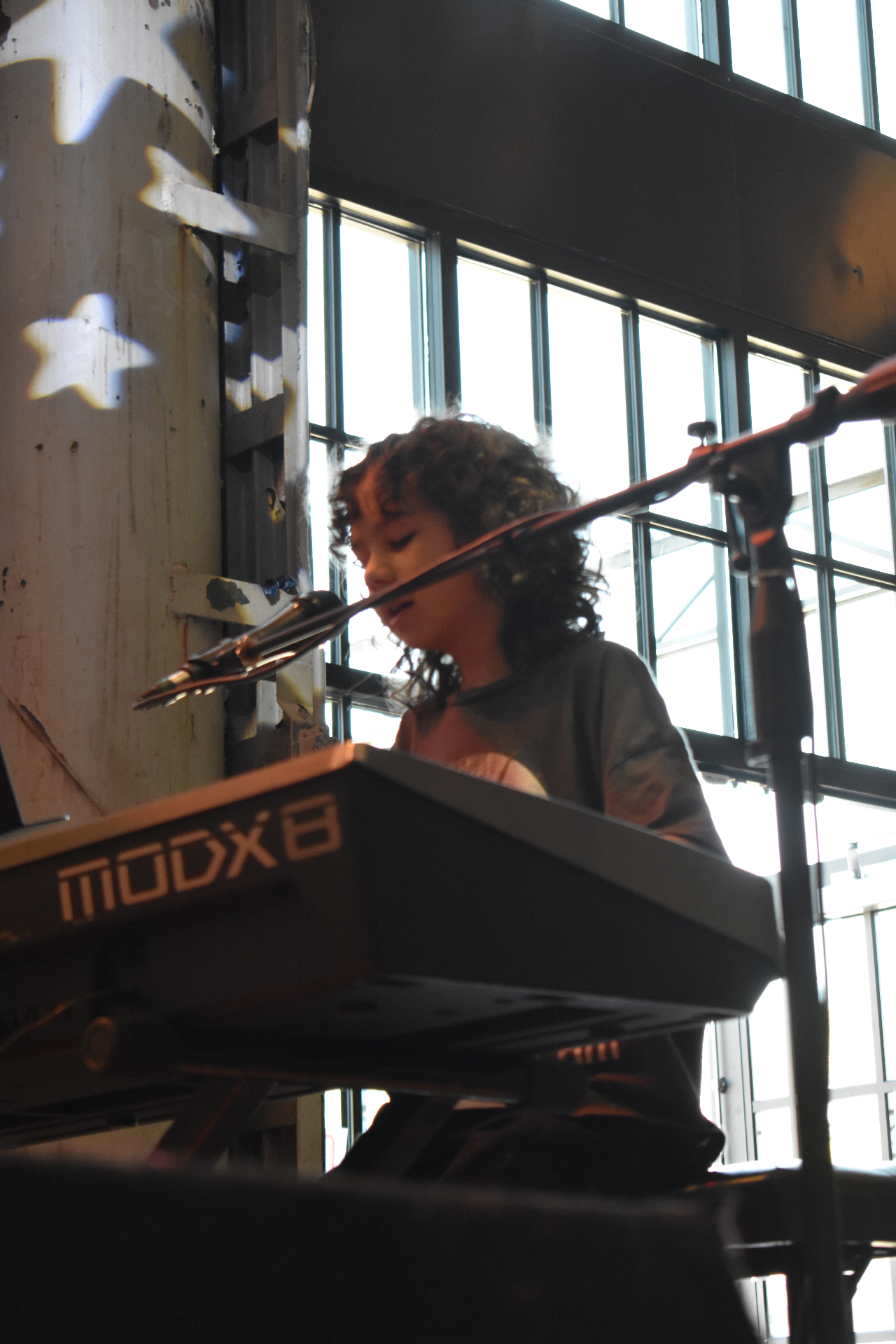Student singing and playing keyboard on stage